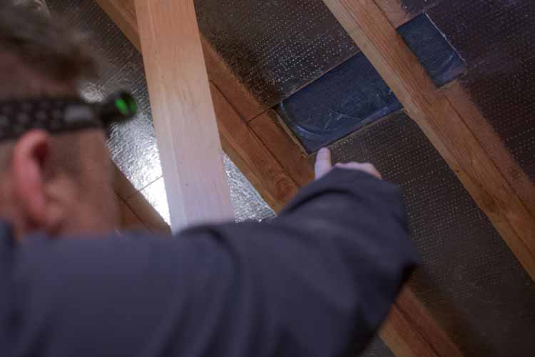 Team member pointing to patched roof from inside the attic