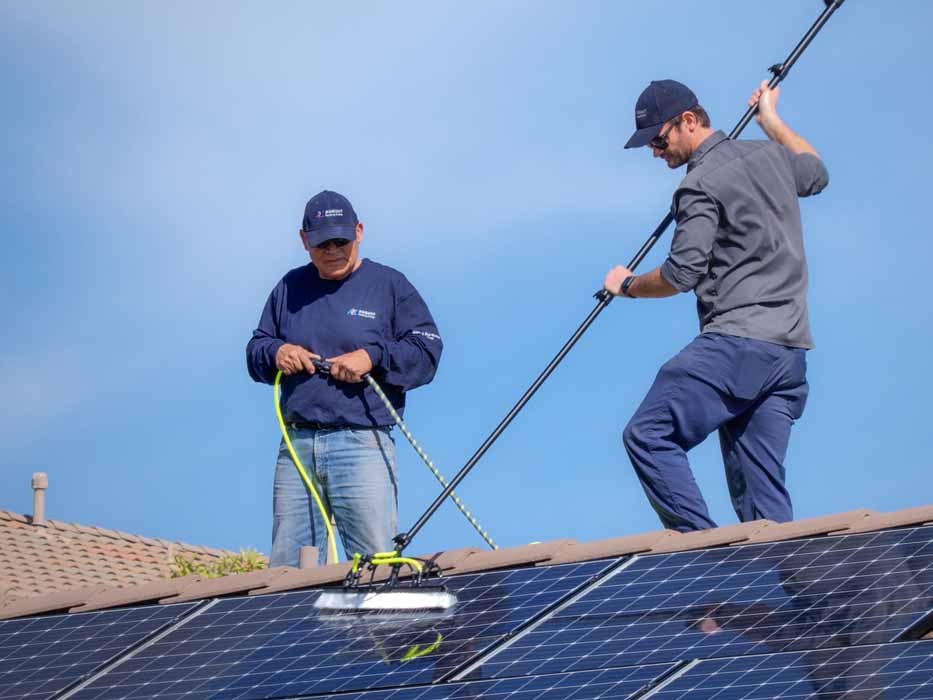 Tech cleaning solar panels on roof